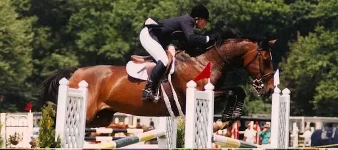 Kristi Smith riding a bay horse over a jump in competition