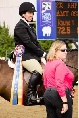 Amy Olszewski on horseback with a tricolor ribbon at CHSA Finals