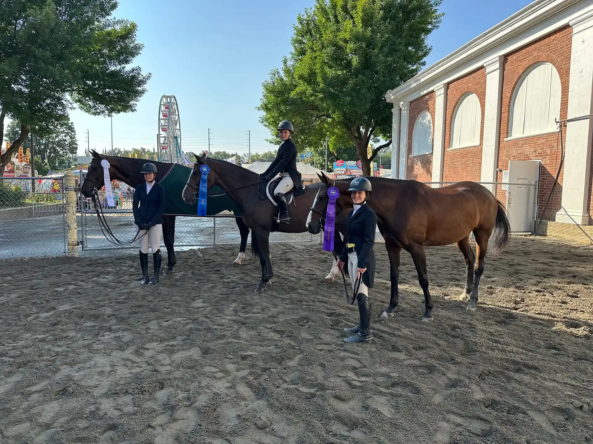 Three young riders with award ribbons at county fair