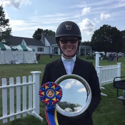 Smiling rider in helmet holding silver platter and tricolor ribbon